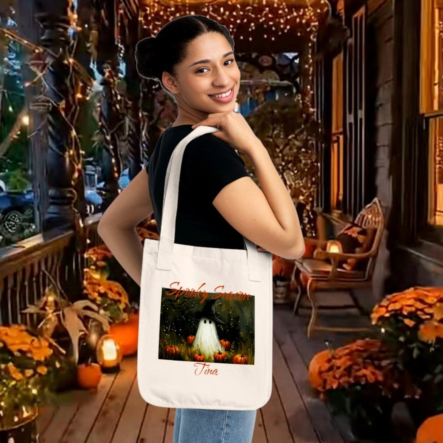 A off white 100% organic cotton tote bag featuring a Halloween-themed illustration of a ghost in a witch hat, surrounded by pumpkins modeled on a lovely fall shopper. Personalize yours in The Fright Factory New Orleans horror gift shop.