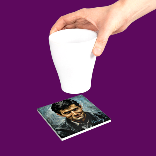 A coffee mug sitting on a custom Norman Bates horror movie coaster on a wooden table, featuring a vintage motel-style design.