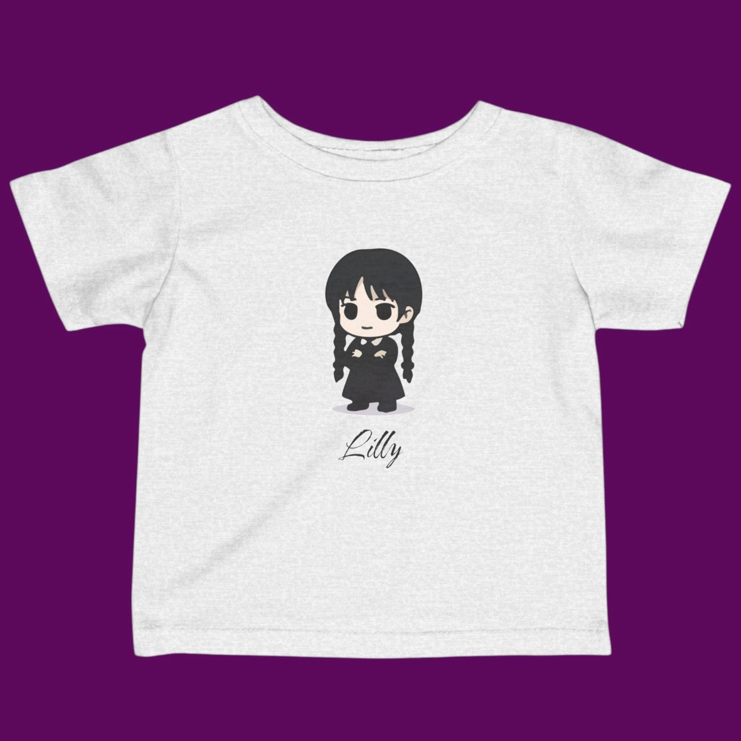 Close-up of a custom Chibi Wednesday Addams inspired goth girl graphic with a personalized name on a off white kids t-shirt. Available in The Fright Factory New Orleans gift shop.