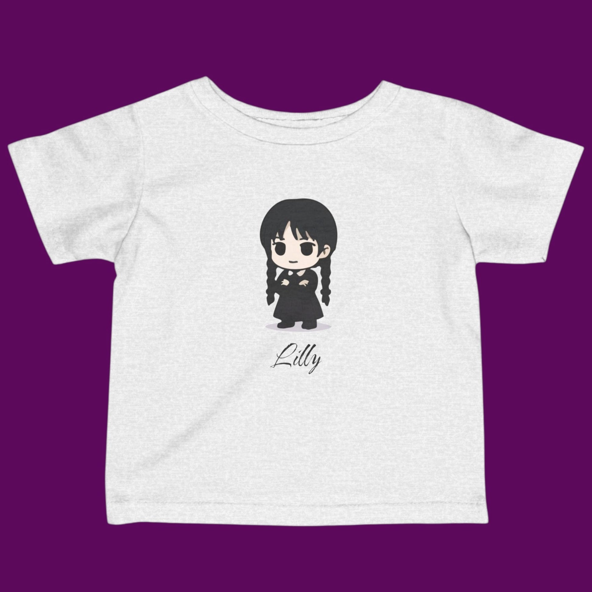 Close-up of a custom Chibi Wednesday Addams inspired goth girl graphic with a personalized name on a off white kids t-shirt. Available in The Fright Factory New Orleans gift shop.