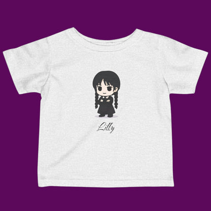Close-up of a custom Chibi Wednesday Addams inspired goth girl graphic with a personalized name on a off white kids t-shirt. Available in The Fright Factory New Orleans gift shop.