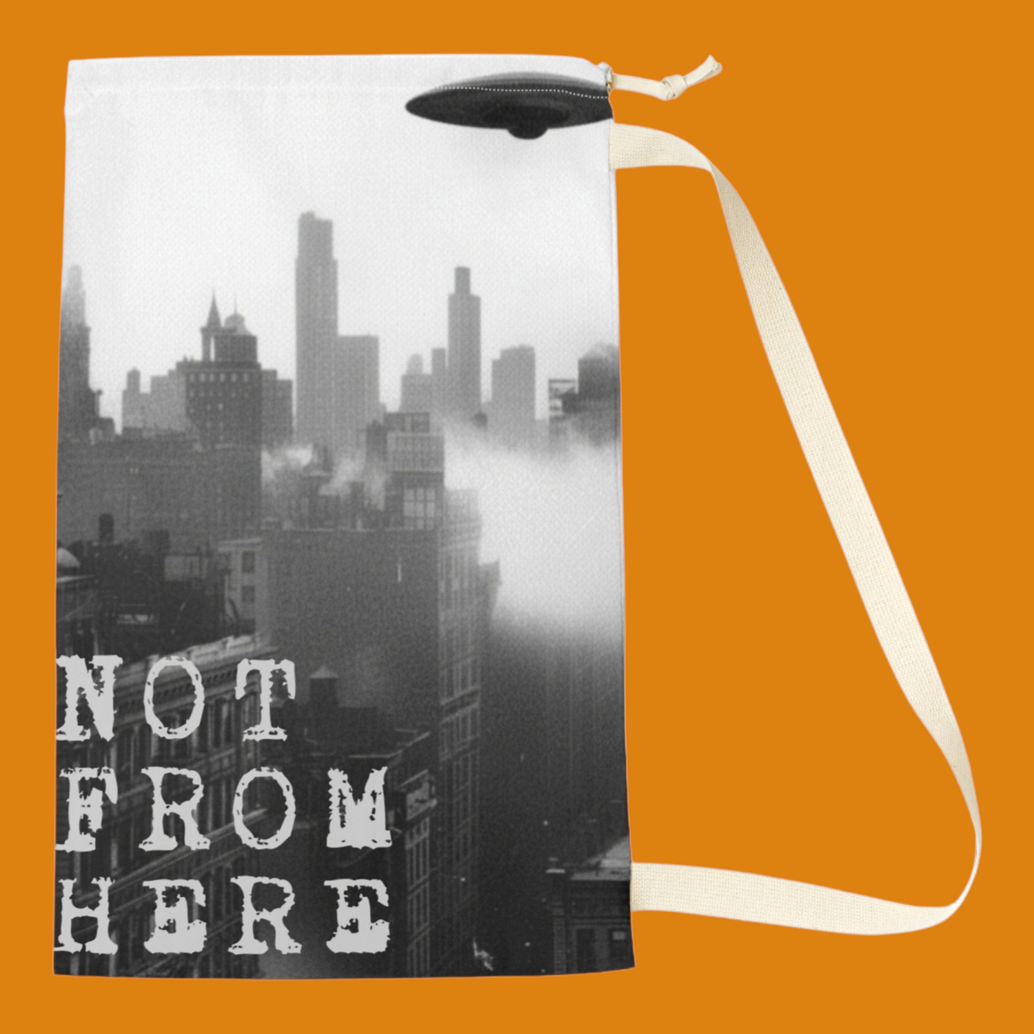 Black and white drawstring laundry bag with vintage 1950s sci-fi art of a UFO flying saucer hovering over a city skyline with Not From Here text. From The Fright Factory New Orleans.