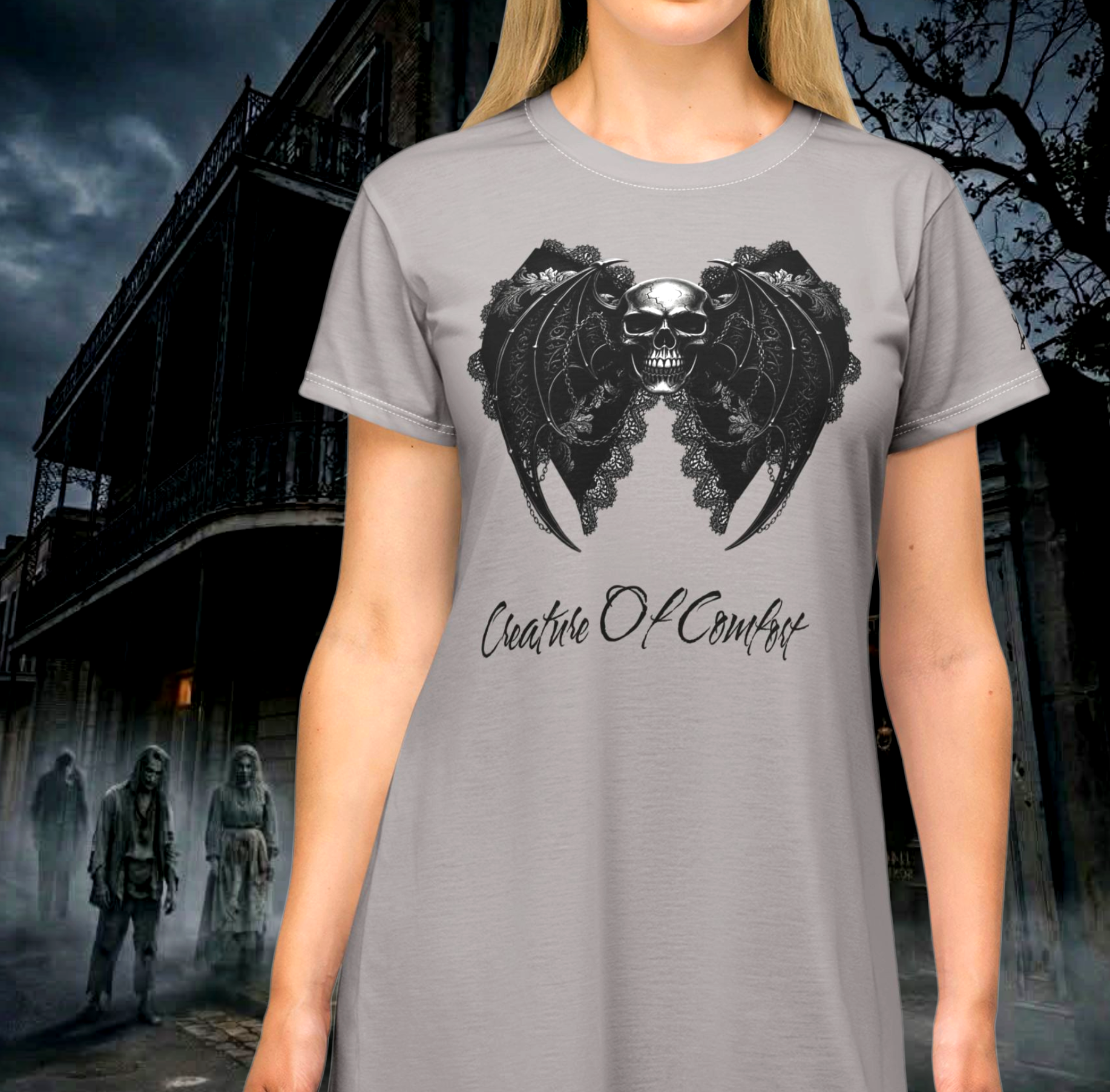 Model wearing the black Creature of Comfort graphic nightshirt styled as a gothic skull dress with a white contrast neck, featuring a bat-wing lace skull illustration for The Fright Factory, New Orleans.