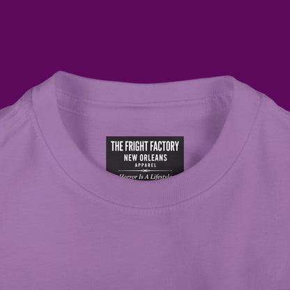 Close-up of a custom Chibi Wednesday Addams inspired goth girl graphic with a personalized name on a purple kids t-shirt. Available in The Fright Factory New Orleans gift shop.